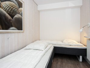 Een compacte kamer met twee bedden, een witte muur en een lijst met schelpen.