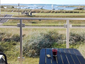 A balcony with a table, a glass of red drink, and a box. - Holiday Home in Wendtorf (Wendtorf)