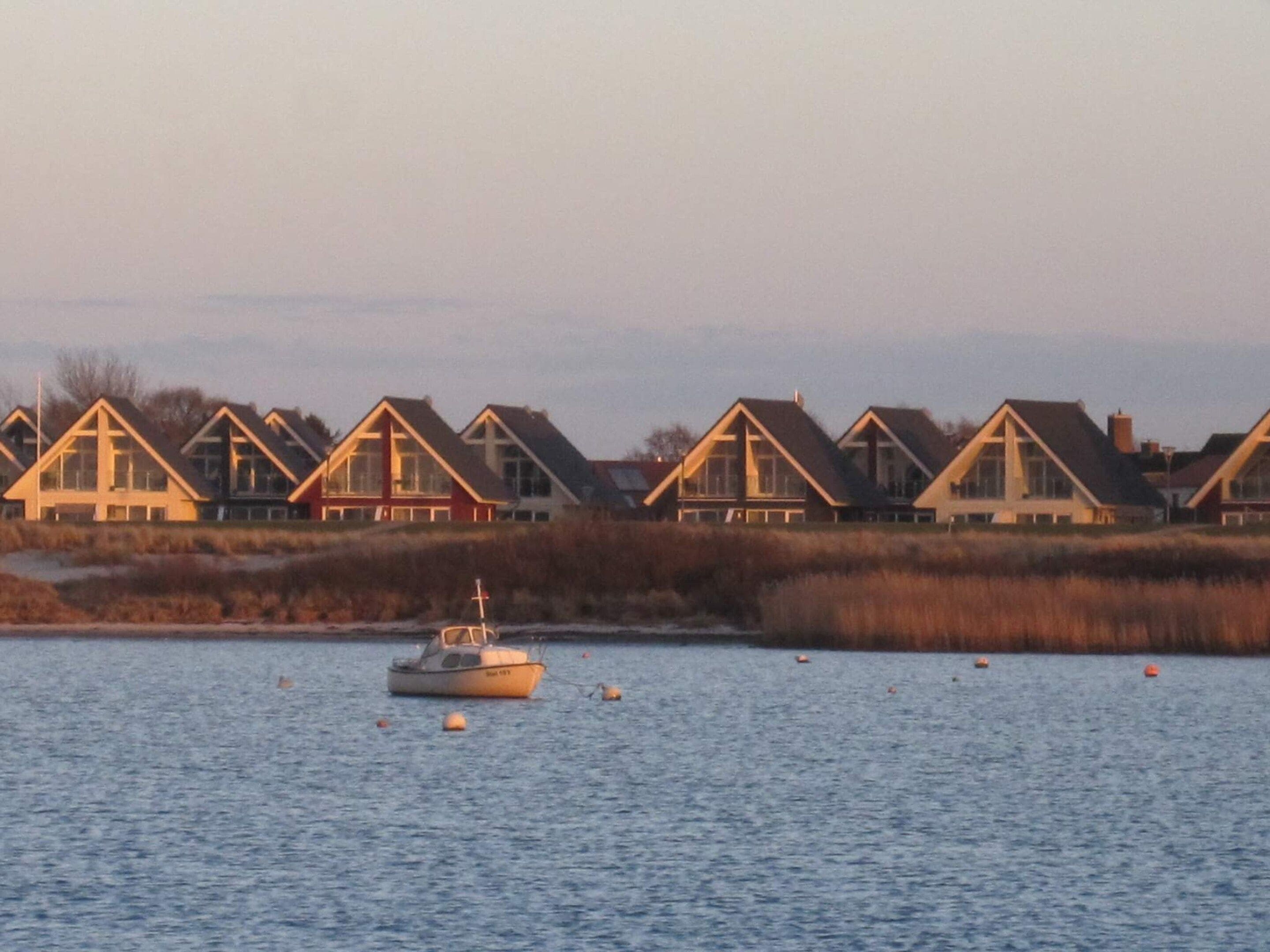 A row of coastal houses with a boat on the water.