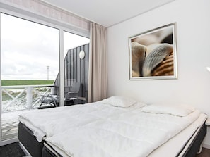 Une chambre d’hôtel avec un lit, une grande fenêtre et un tableau encadré au mur.