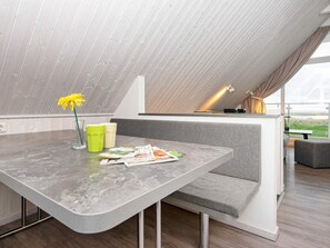 A modern loft bedroom with a sloped ceiling, a built-in bench, and a dining table.