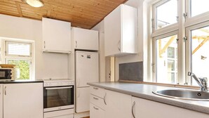 Een compacte keuken met witte kasten, een inbouwoven, een magnetron en een spoelbak.