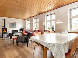 A cozy living room with a fireplace, a dining table, and a kitchen area.