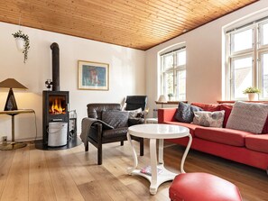 A cozy living room with a fireplace, a red sofa, a leather armchair, and a small round table.