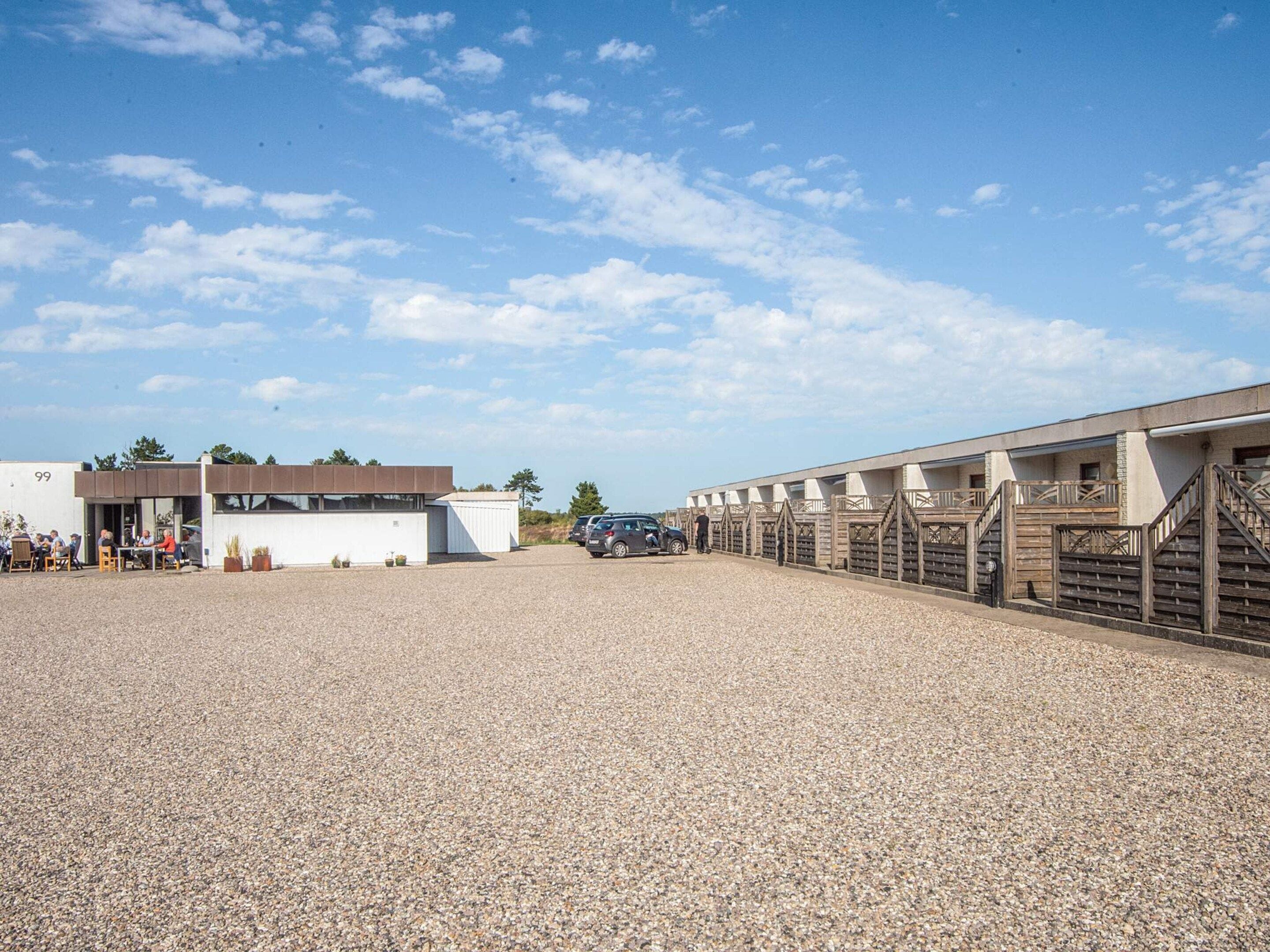 A gravel parking area with a building and a covered walkway.