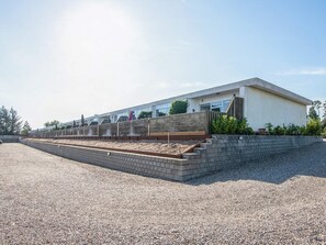 Un bâtiment moderne doté d’un toit plat, d’un mur de soutènement en briques et d’une allée gravillonnée.