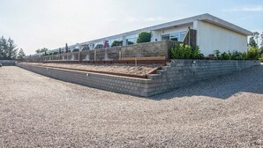 A modern building with a flat roof, large windows, and a gravel driveway.