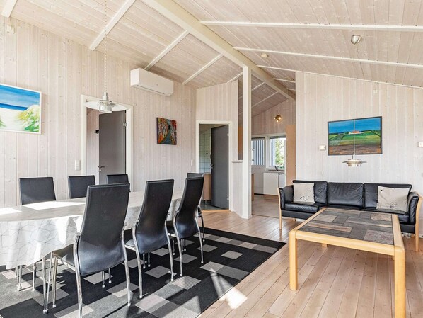 A spacious room with a dining area, a sofa, and a kitchen in the background. - 6 Person Holiday Home in Rudkobing (Rudkobing)