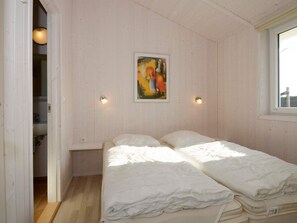 A room with two beds, a painting on the wall, and a window.