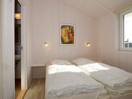 A room with two beds, a painting on the wall, and a window.