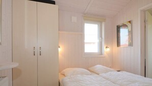 A bedroom with a bed, a wardrobe, a window, and a wall-mounted light fixture. - Holiday Home in GrÃ¶mmitz (Groemitz)