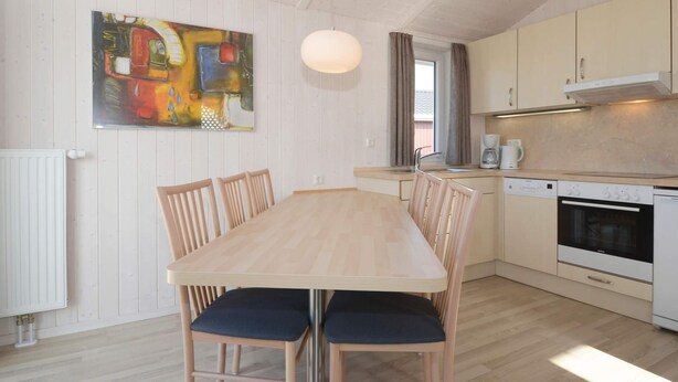 A modern kitchen with a dining table, chairs, and a painting on the wall. - Holiday Home in GrÃ¶mmitz (Groemitz)