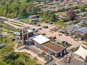 An aerial view of a commercial area with a prominent building featuring a flat roof and a large open space with outdoor seating. - Holiday Home in GrÃ¶mmitz (Groemitz)