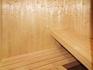Una sauna de madera con bancos y suelo inclinado.