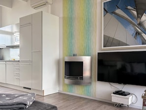 A modern kitchen with white cabinets, a built-in microwave, and a colorful vertical stripe wall. - Holiday Home in Wendtorf (Wendtorf)