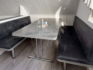 A modern interior with a marble table, black cushioned seating, and a small decorative item. - Holiday Home in Wendtorf (Wendtorf)