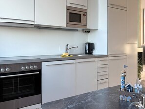 A modern kitchen with a built-in oven, a microwave, a coffee maker, and a sink. - Holiday Home in Wendtorf (Wendtorf)