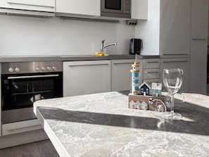 A kitchen with a marble countertop, a small lighthouse model, a wine glass, and a microwave. - Holiday Home in Wendtorf (Wendtorf)