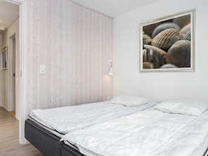 A bedroom with a bed, a wall-mounted light, and a framed picture.