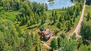 A rural landscape with a lake, a red barn, and a dirt road. - 4 Star Holiday Home in Sturefors (Sturefors)