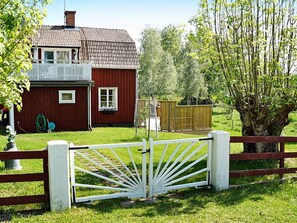 A red house with a white gate, a tree, and a grassy yard. - 4 Star Holiday Home in Sturefors (Sturefors)