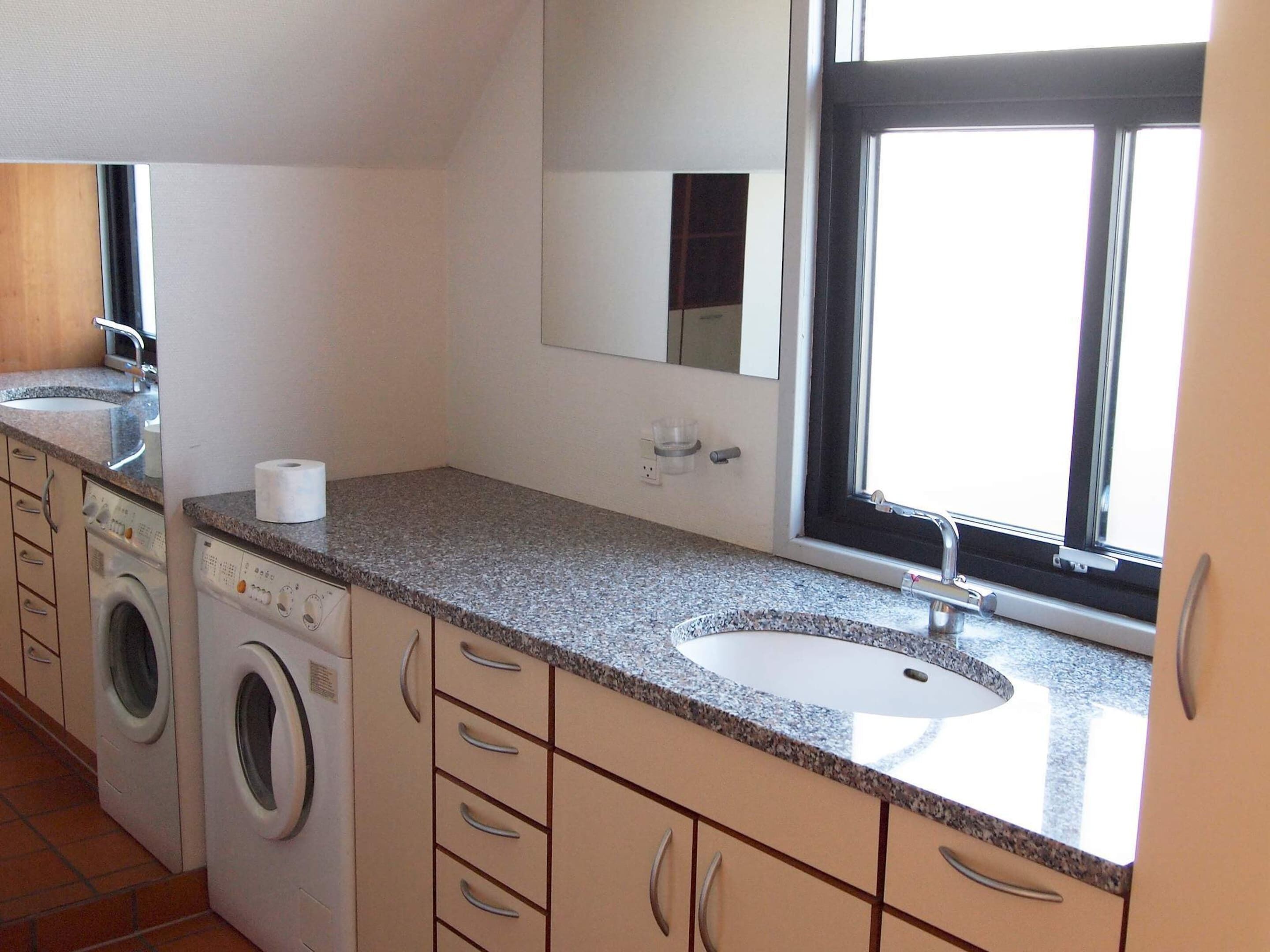 A compact kitchen with a sink, a washing machine, and a countertop.