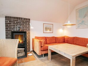 A living room with a brick fireplace, a sofa, a wooden coffee table, and a map on the wall.