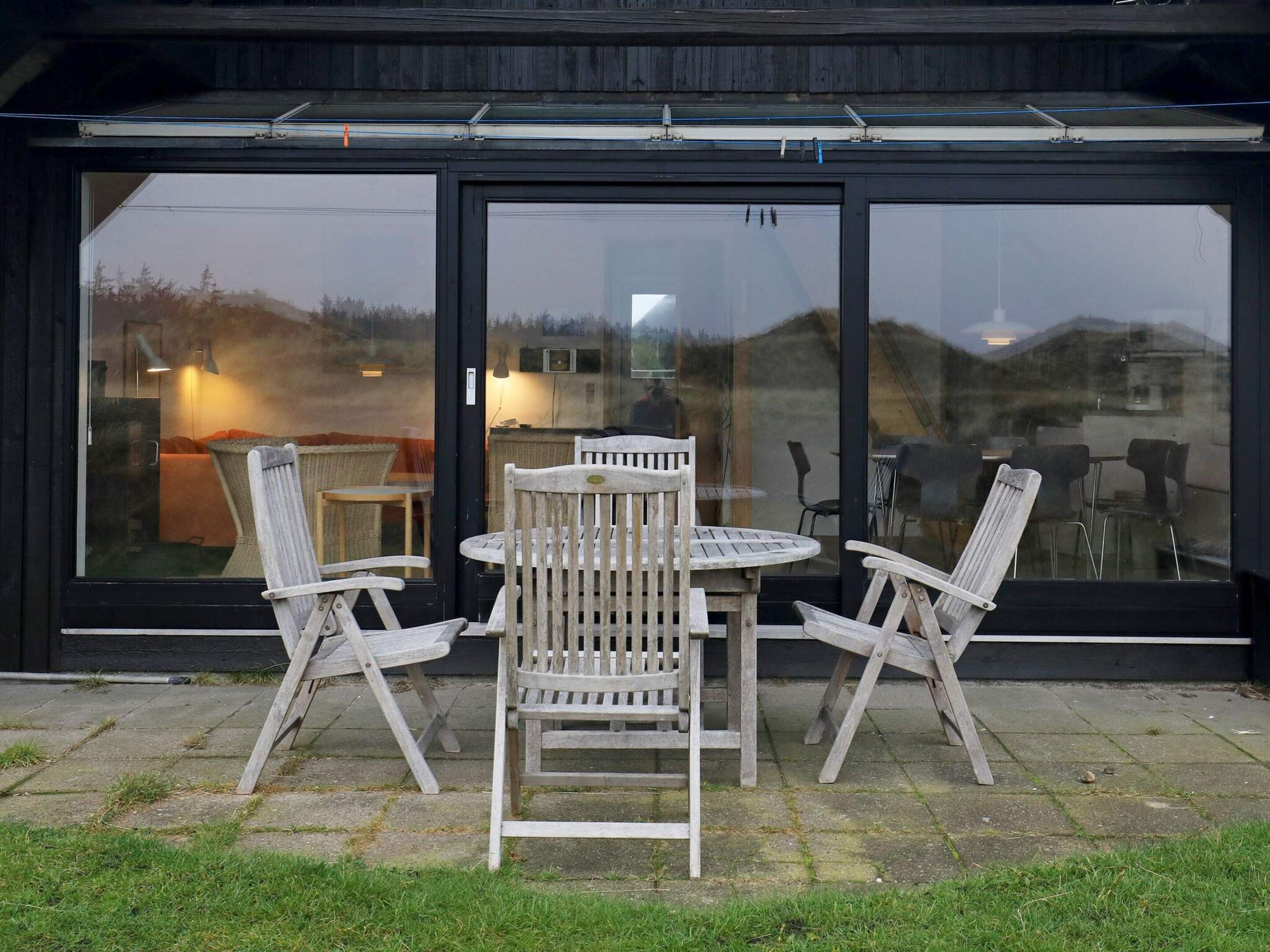 A patio area with a table and four chairs, a glass door, and a view of the outside.