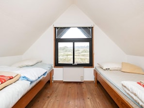 A small, triangular room with two beds, a window, and a radiator. - Serene Holiday Home in Pandrup near Sea (Pandrup)