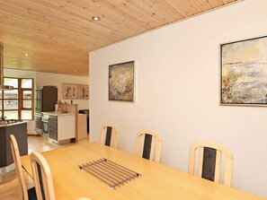 A dining area with a wooden table, chairs, and artwork on the walls.