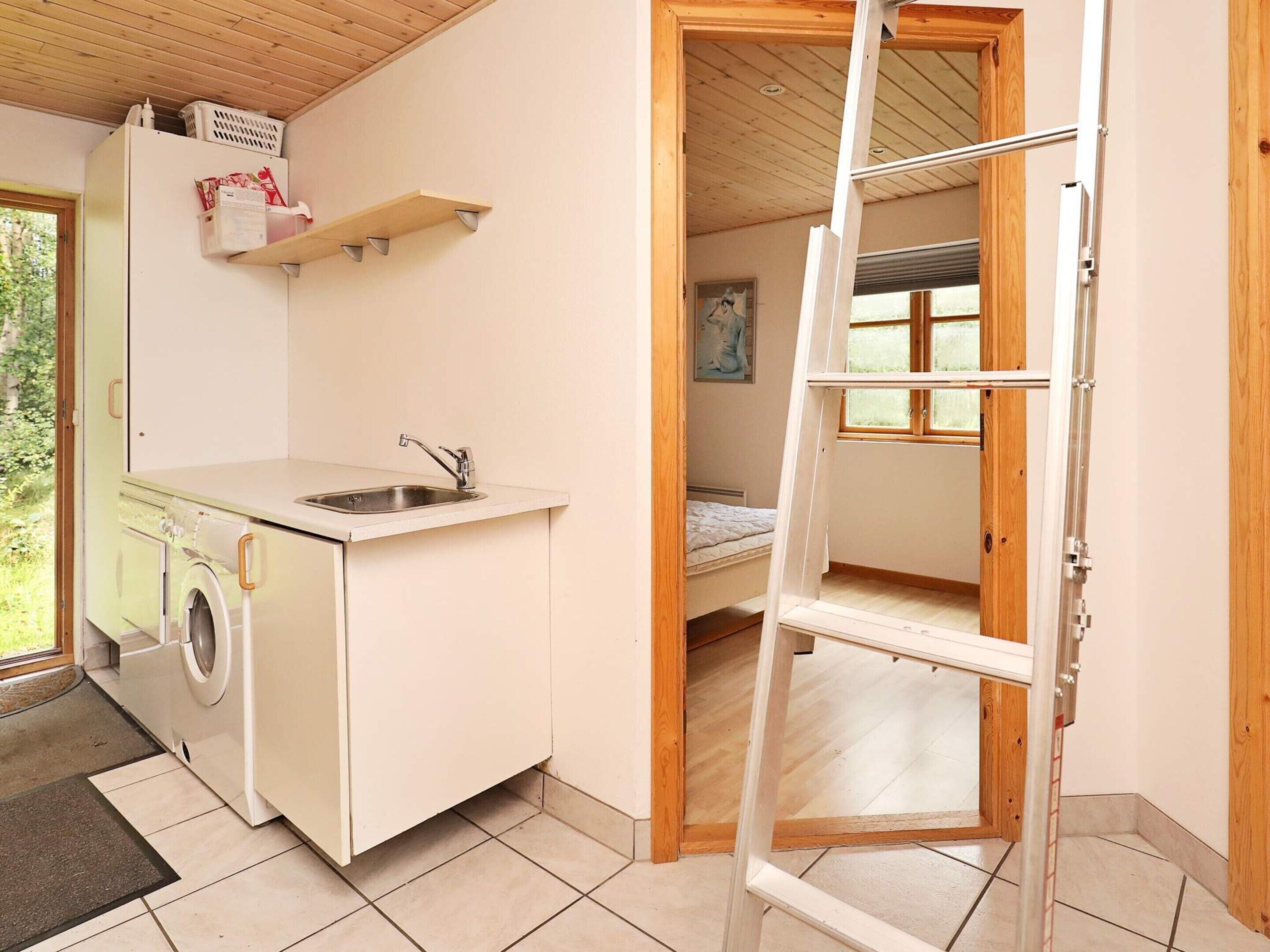Una cocina compacta con lavadora, un lavamanos y una ventana.