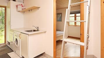 Una cocina compacta con lavadora, un lavamanos y una ventana.