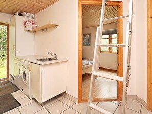 A compact kitchen with a washing machine, a sink, and a window.