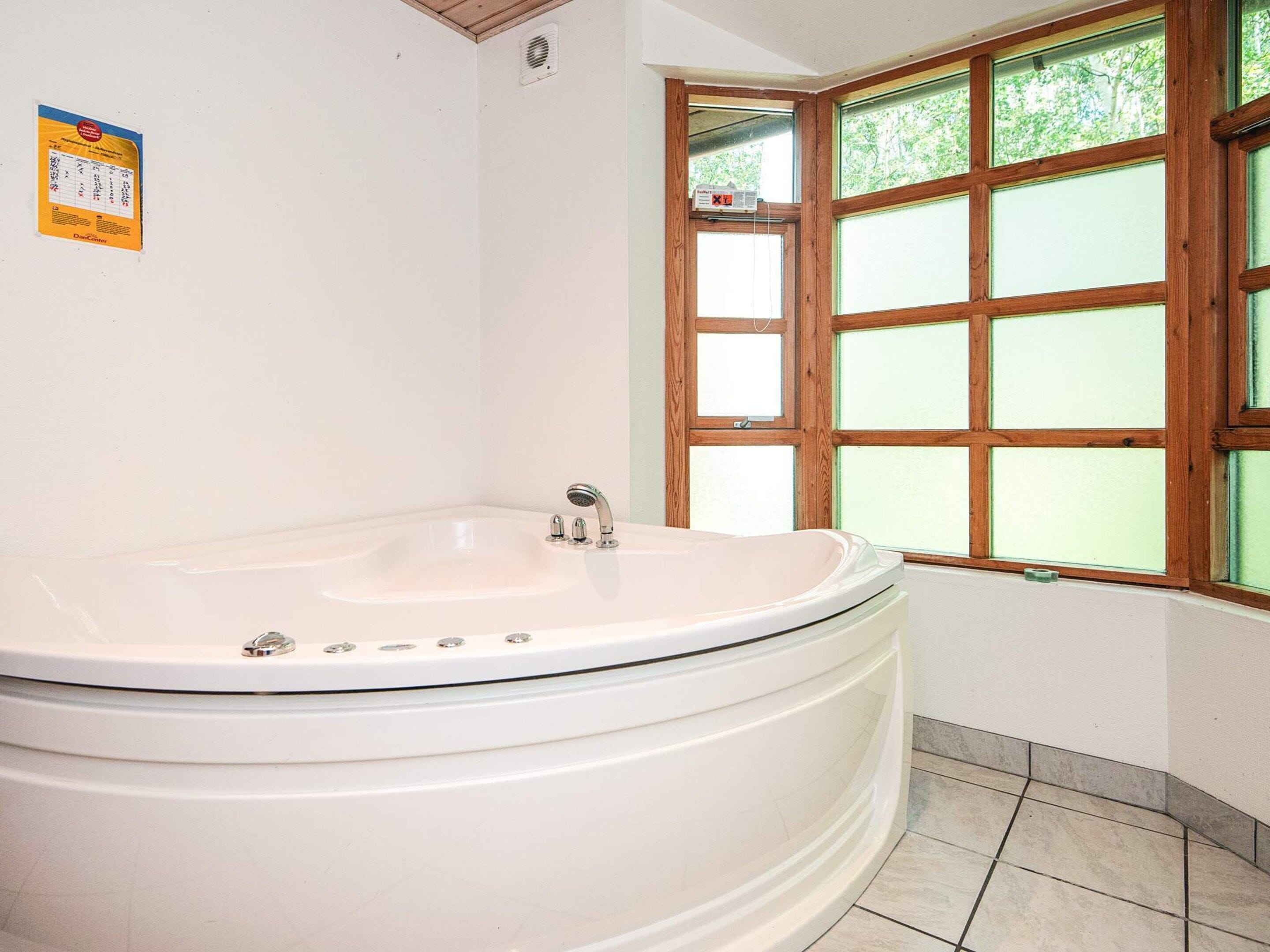 A bathroom with a freestanding bathtub, a window with wooden frames, and a wall-mounted heater.