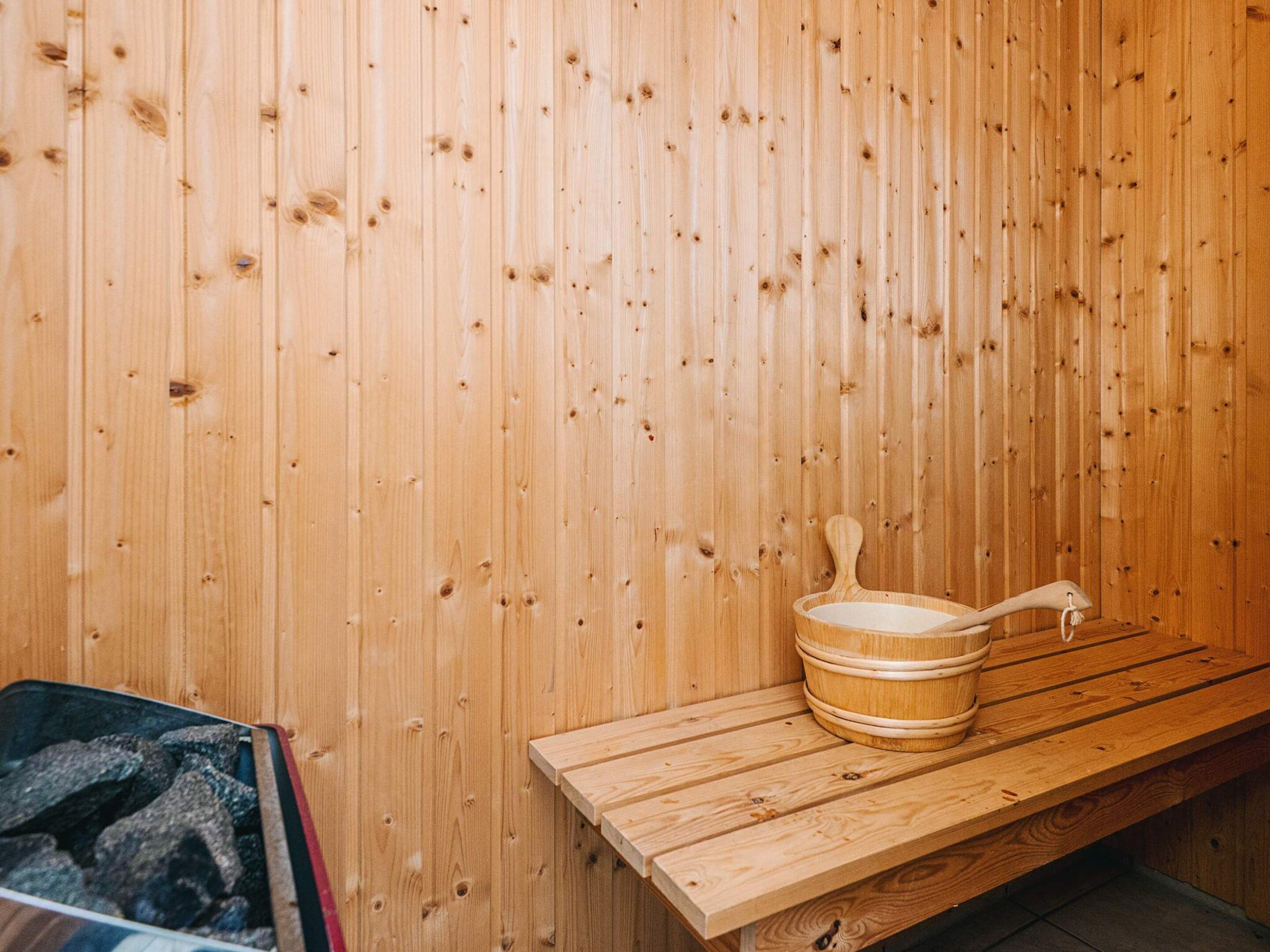 A wooden sauna with a bench and a wooden bucket.