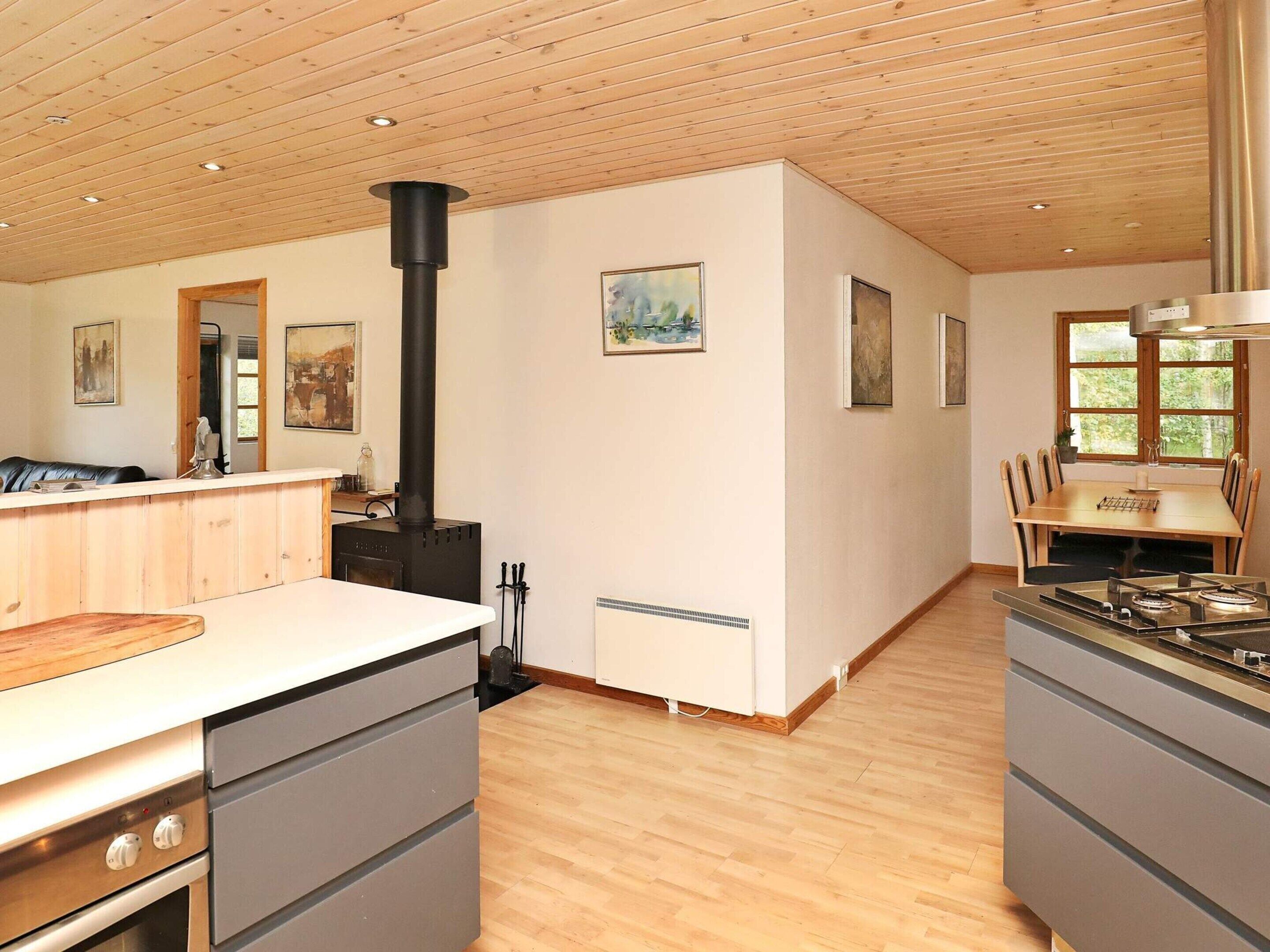 A modern kitchen with a central island, a stove, and a dining area with a table and chairs.