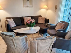 A living room with a dark-colored sofa, two armchairs, a coffee table, and a potted plant with pink flowers. - 8 Person Holiday Home in Gjern-by Traum (Gjern)