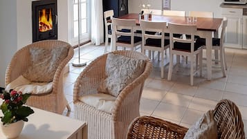 Una sala acogedora con muebles de mimbre, chimenea, mesa de comedor y zona de cocina.
