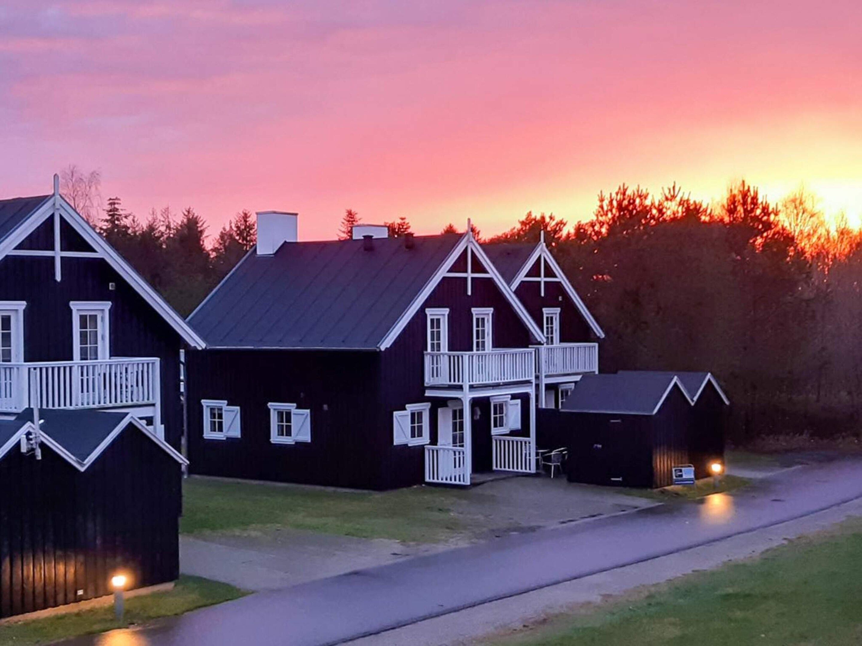 A row of black wooden buildings with white trim and balconies, likely a historic or traditional lodging area.