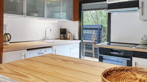Una cucina moderna con mobili in legno, un lavello in acciaio inox, una macchina da caffè e vista sull'esterno.