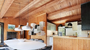 Una cucina moderna con rivestimenti in legno, un'isola centrale e un'area pranzo con un tavolo rotondo e sedie.
