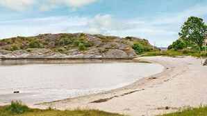 Ein Strand mit einem Felsen im Hintergrund und einem Gebäude auf der rechten Seite.