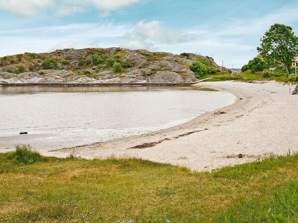 Une plage avec une formation rocheuse en arrière-plan et un bâtiment sur la droite.