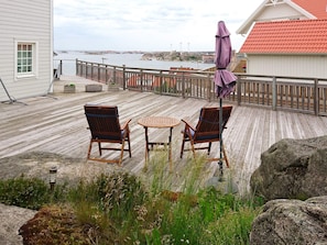 Een houten terras met twee stoelen en een tafel, met uitzicht op een wateroppervlak.