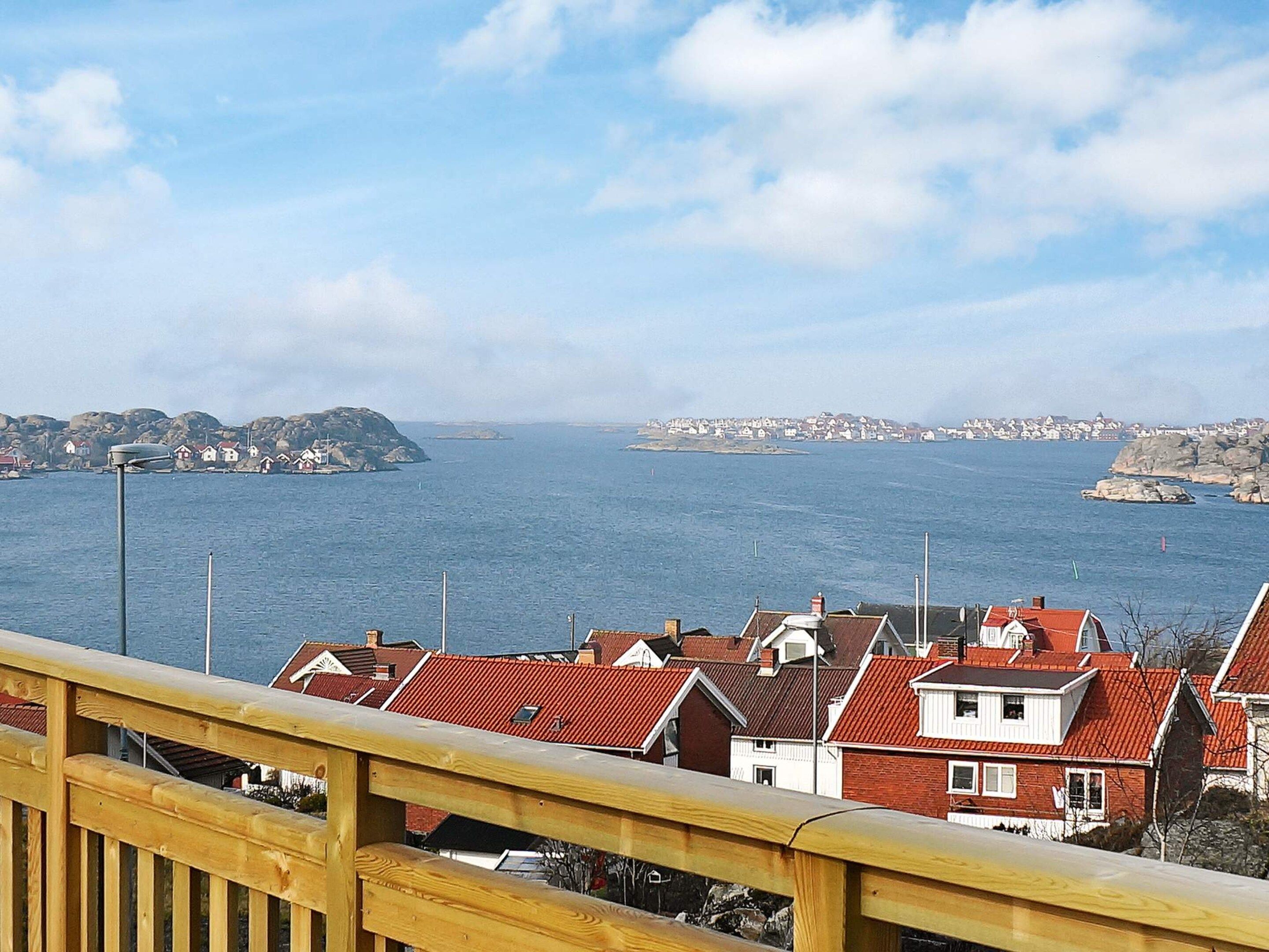 Un pueblo costero con casas de tejados rojos, una barandilla de madera y vistas al mar.
