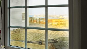 Ein Fenster mit Blick auf eine Holzterrasse und einen gelben Zaun.