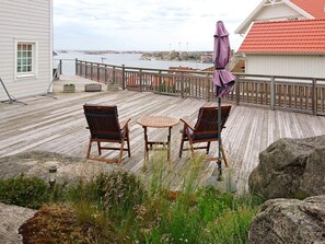 A wooden deck with two chairs and a table, overlooking a body of water.