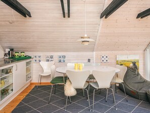 A modern kitchen with white cabinets, a dining area with white chairs, and a black and white patterned floor. - 6 Person Holiday Home in Fano (Fano)