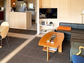 Moderni olohuone, jossa on puinen sohvapöytä, sohva ja televisio.