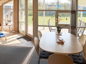 A spacious room with a large window, a round table, and a seating area. - Cozy Holiday Home in Lolland near Beach (Nakskov)